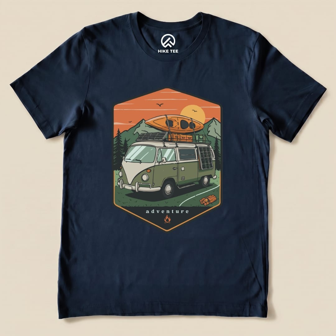A navy graphic t-shirt featuring a vintage camping van with a kayak on top and the word "adventure" printed below.