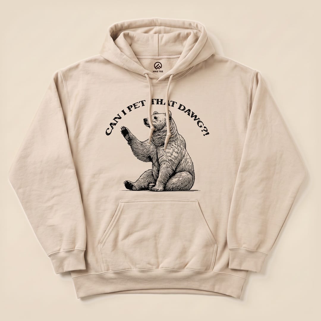 A beige hoodie features a playful graphic of a bear waving with the text "CAN I PET THAT DAWG?!" above it, showcasing the Can I Pet That Dawg Bear Hoodie design.