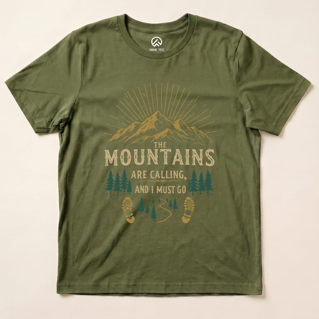 The olive green graphic t-shirt features a mountain scene with the slogan "THE MOUNTAINS ARE CALLING, AND I MUST GO" printed in bold lettering.