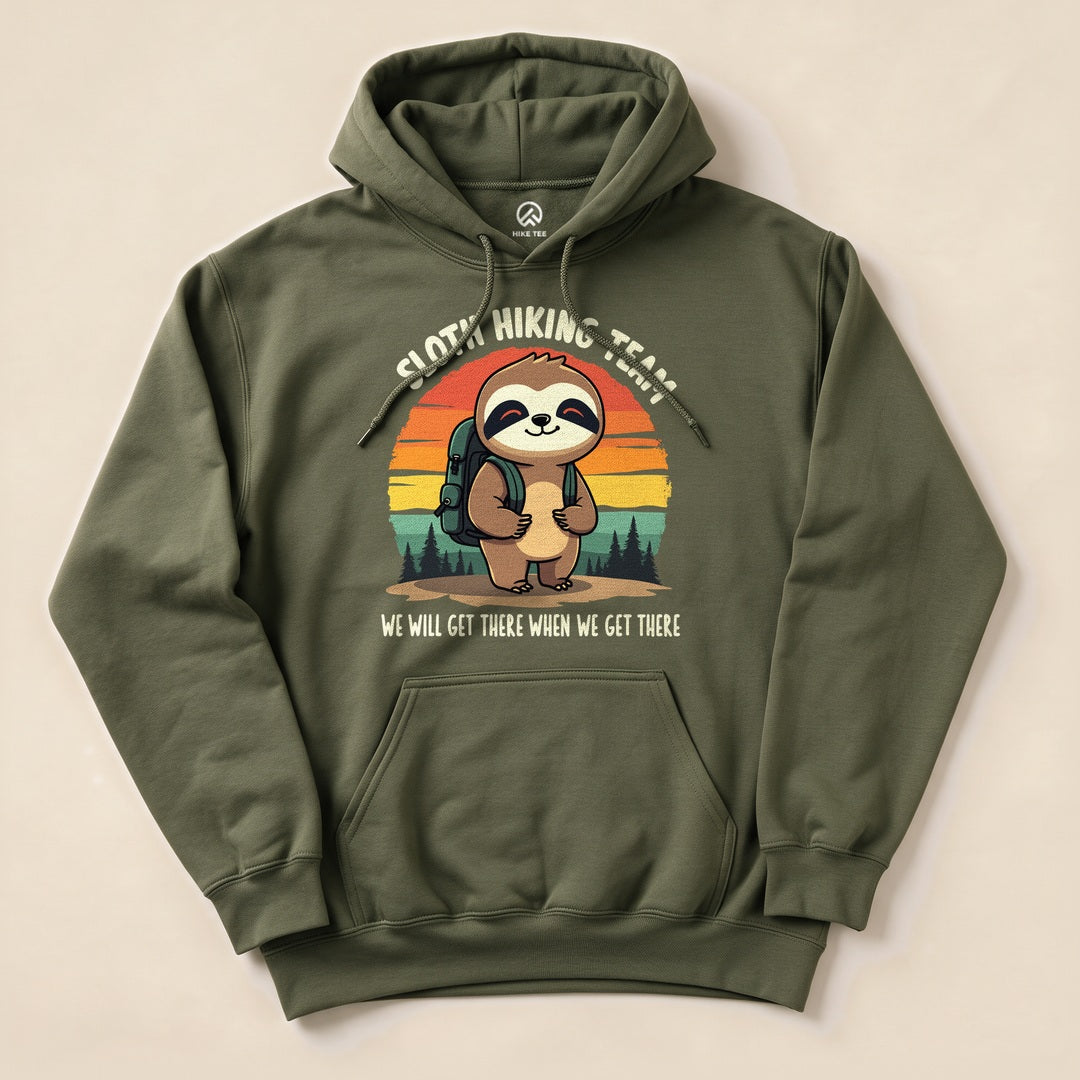 Olive green hoodie featuring a sloth with a backpack, surrounded by trees and a sunset, labeled "Sloth Hiking Team Forest Hoodie".
