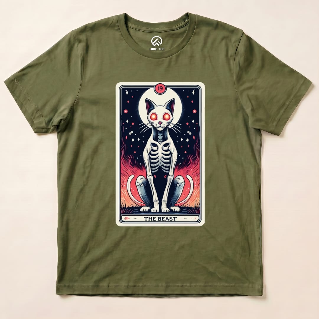 A graphic t-shirt featuring "The Beast Tarrot Cat" design with a skeletal cat and vibrant flames in an olive green color.