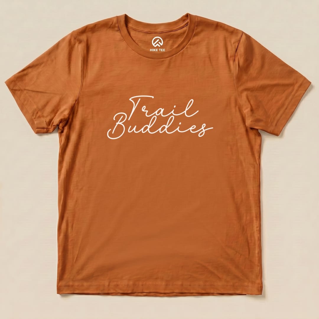 A flat, orange graphic t-shirt featuring the phrase "Trail Buddies" in a playful white script font.