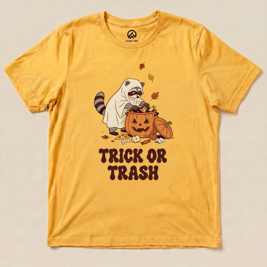 Gold Trick or Trash Shirt with a raccoon in a ghost costume raiding a pumpkin candy bucket graphic