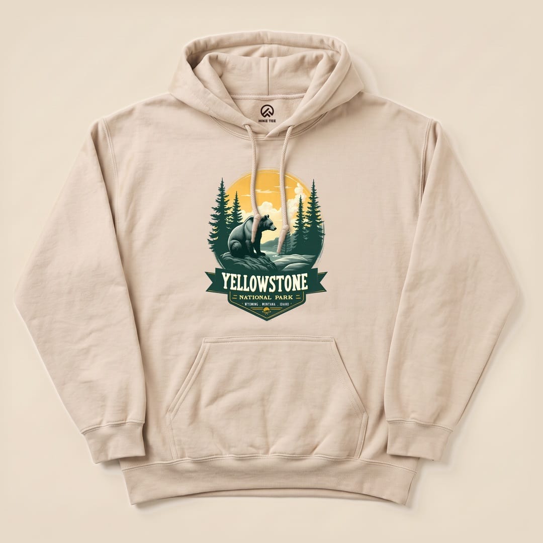 A beige Yellowstone Grizzly Bear Hoodie featuring a graphic of a bear with trees and mountains against a sunset backdrop.