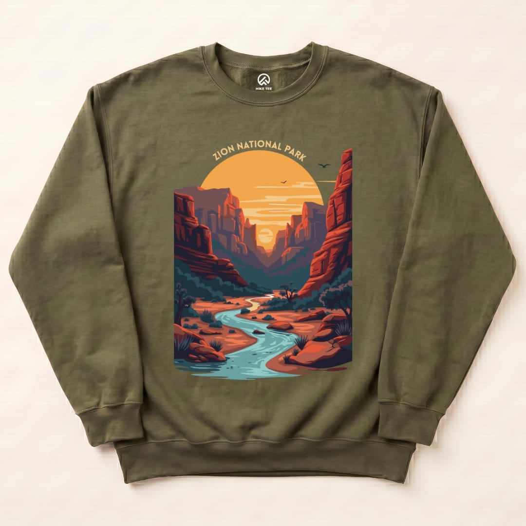A graphic sweatshirt featuring a colorful illustration of Zion National Park with a river and sunset, labeled "Zion National Park.
