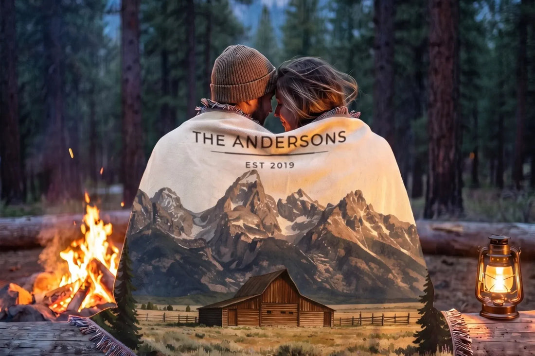 Couple wrapped in a Grand Teton Barn woven blanket by a campfire in the forest