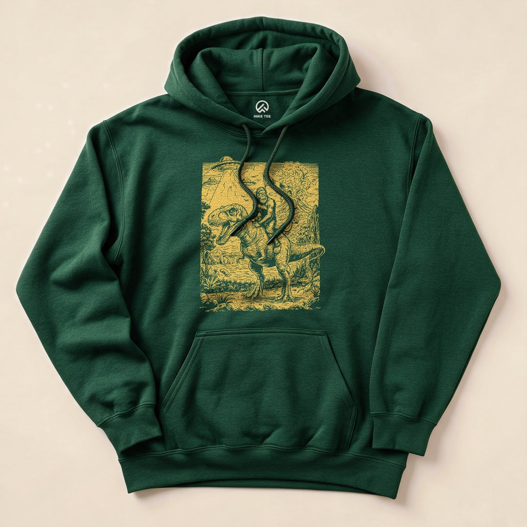 A green hoodie featuring a graphic of a dinosaur with a rider, titled "Bigfoot Dinosaur Hoodie," on a nature-themed background.