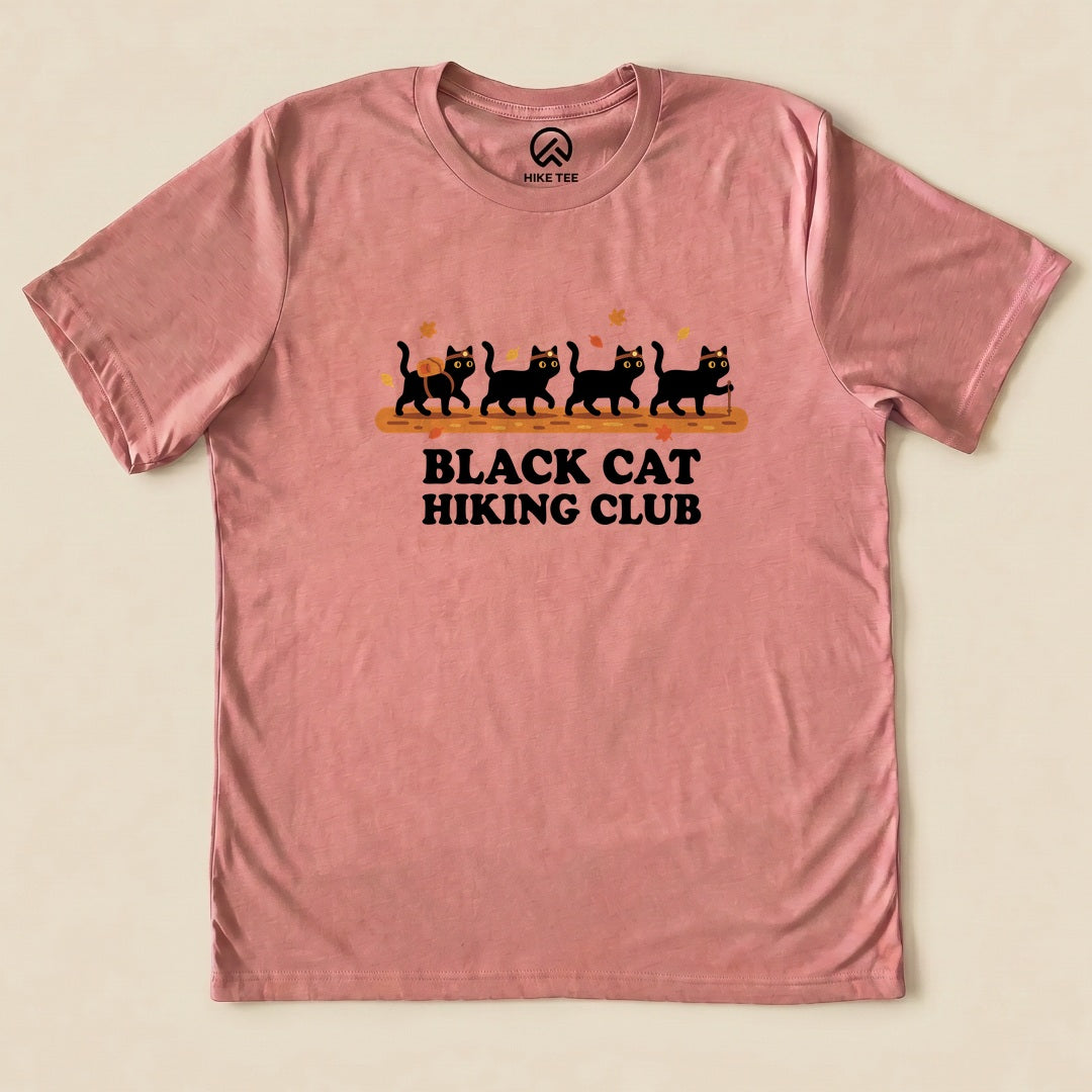 Heather Mauve Black Cat Hiking Club Shirt with a row of black cats walking on a log with autumn leaves graphic