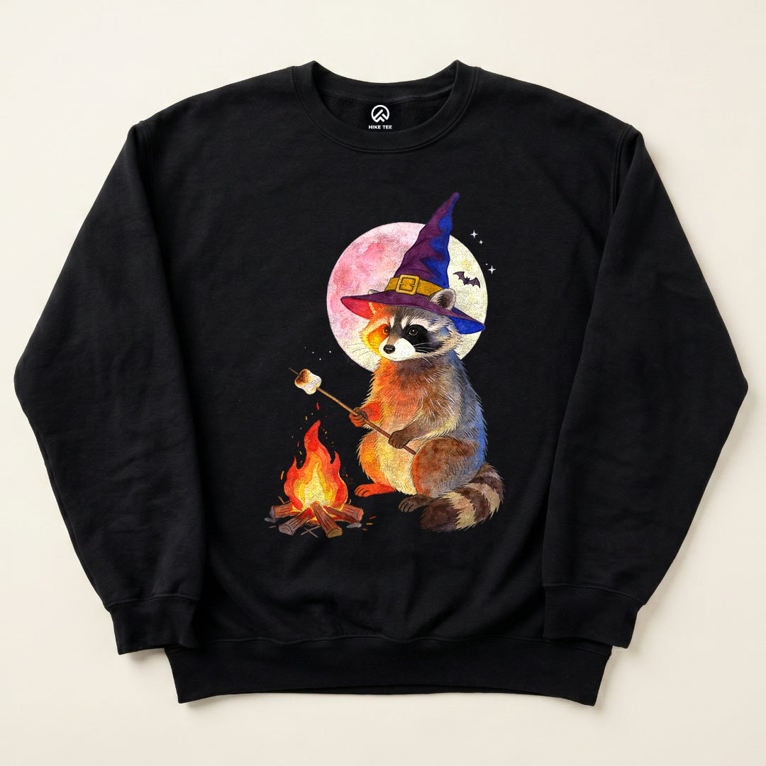 Black Raccoon Witch Campfire Sweatshirt with a raccoon in a witch hat roasting a marshmallow by the campfire graphic