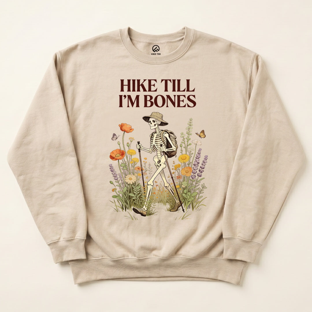 Sand Hike Till I'm Bones Sweatshirt with a skeleton hiker walking through wildflowers graphic