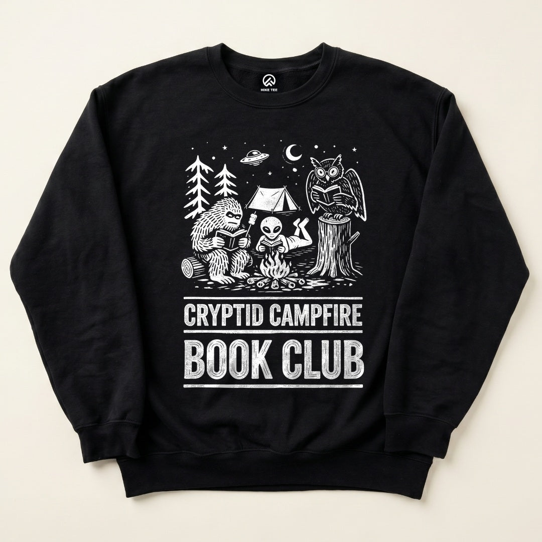 Black Cryptid Campfire Book Club Sweatshirt with a Bigfoot and friends reading around a campfire graphic