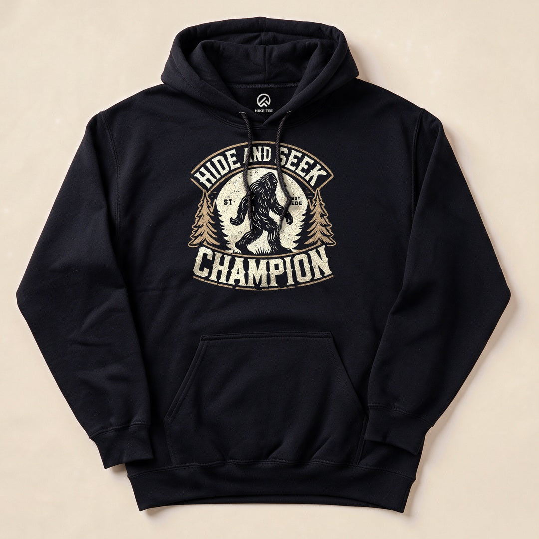 The image features a "Hide and Seek Champion Bigfoot Hoodie" in black, showcasing a graphic of Bigfoot among trees with the slogan “Hide and Seek Champion.”