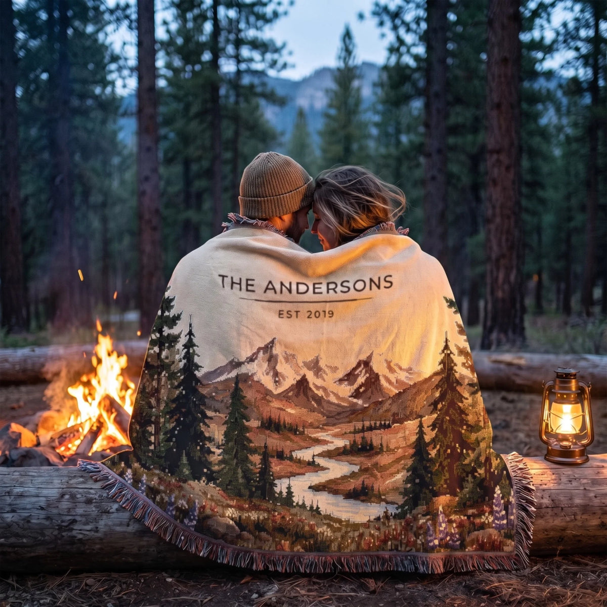 Couple wrapped in the personalized Mountain River Wildflower Woven Blanket by a campfire