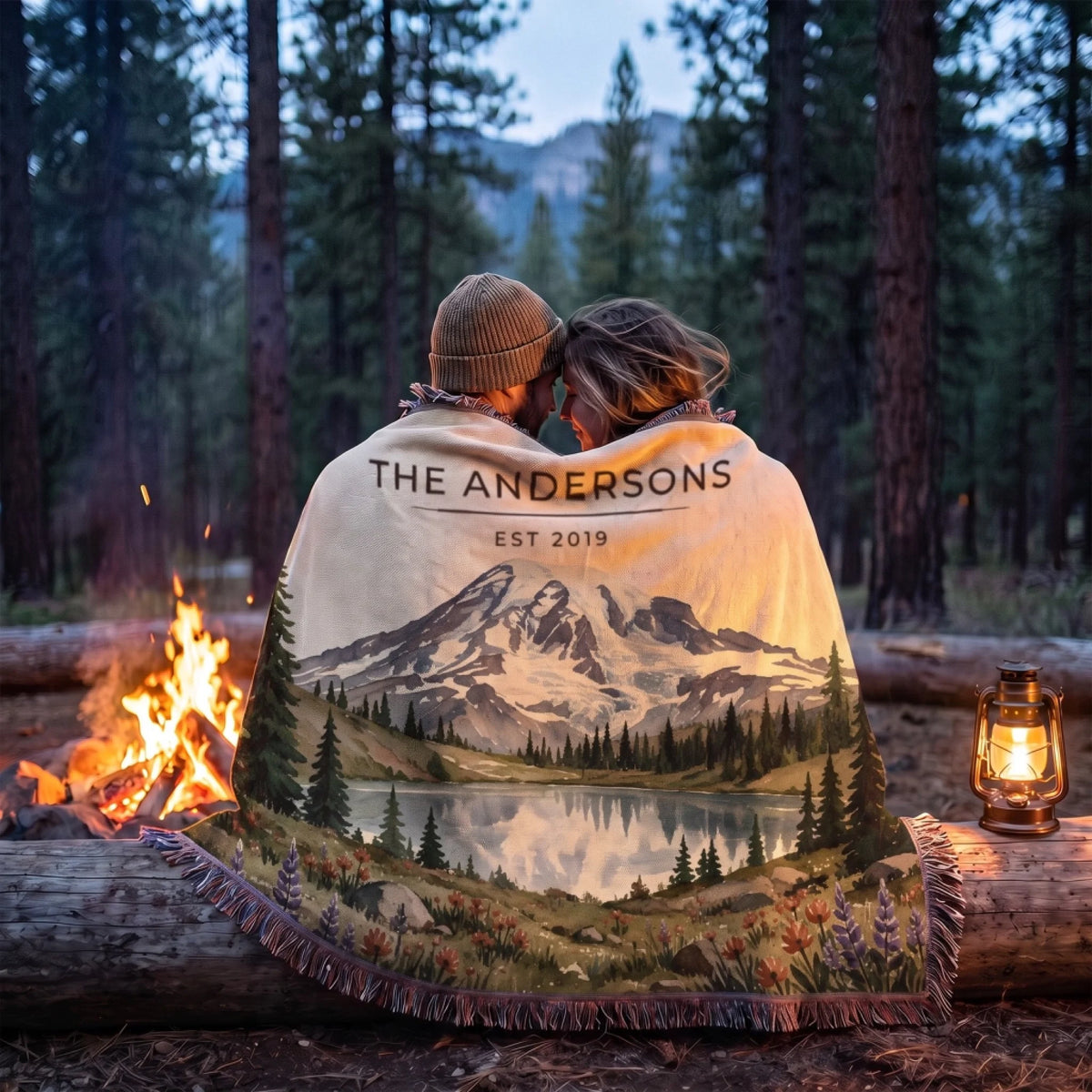 Couple wrapped in the Mount Rainier Lake Woven Blanket by a campfire