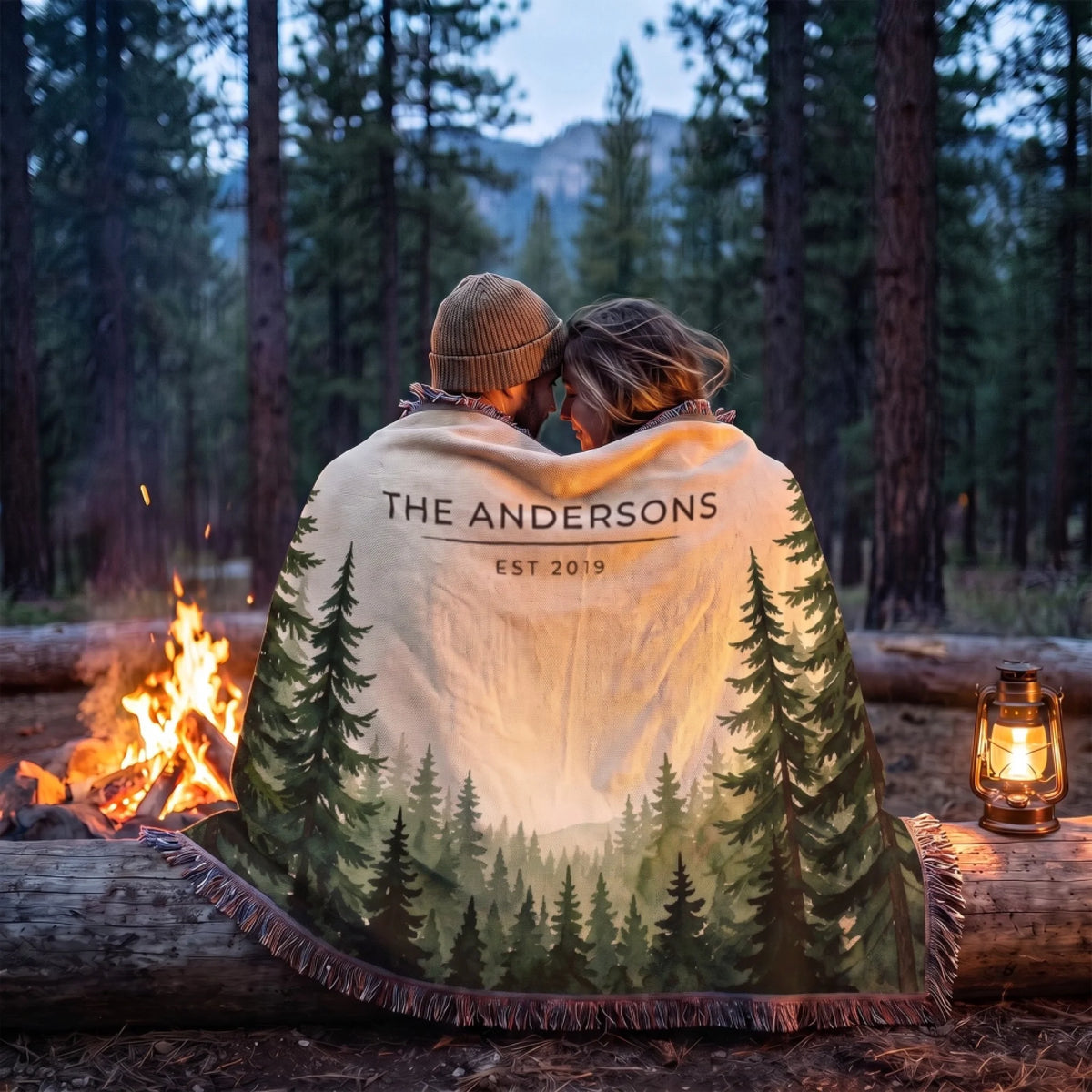 Couple wrapped in the Evergreen Forest Treetops Woven Blanket by a campfire