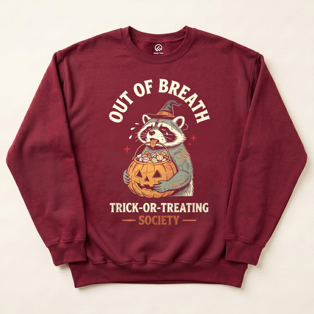 Maroon Out of Breath Trick-or-Treating Society Sweatshirt with a tired raccoon holding a jack-o-lantern candy bucket graphic