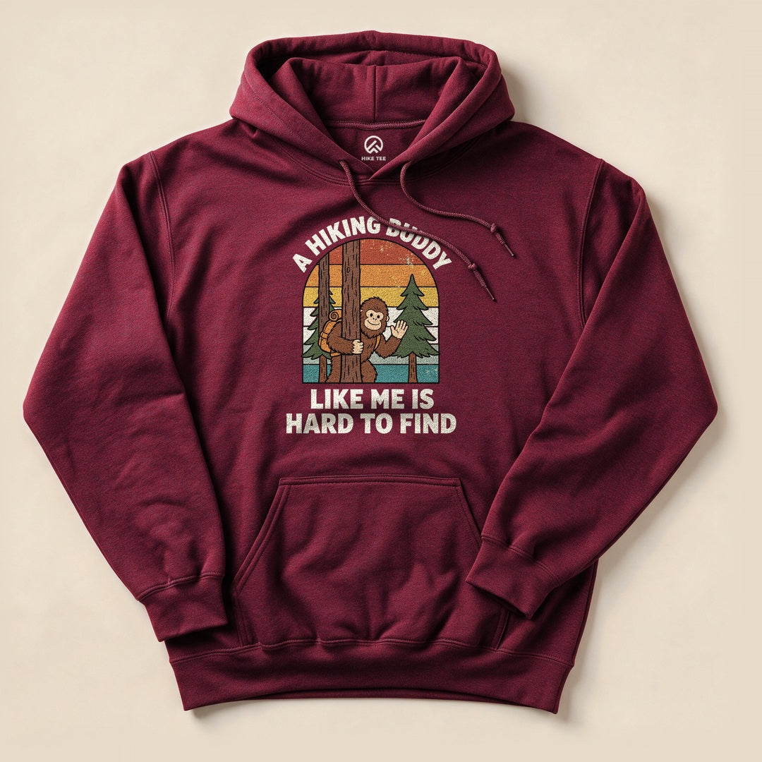 A maroon hoodie featuring a whimsical graphic of a monkey peeking from behind a tree with the text "A Hiking Buddy Like Me Is Hard To Find.