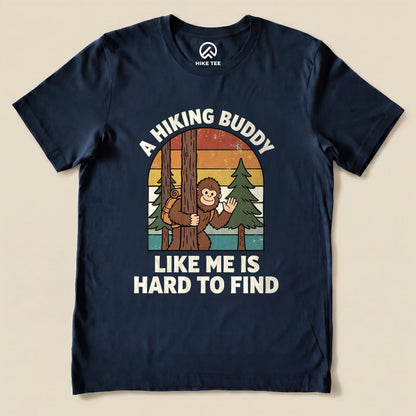 The graphic t-shirt features a playful design of a monkey hiding behind a tree, accompanied by the slogan "A Hiking Buddy Like Me Is Hard To Find.