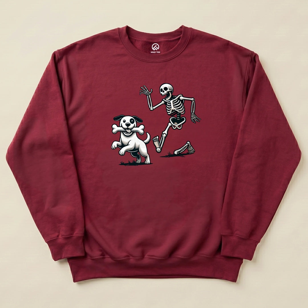 Graphic t-shirt featuring a skeleton and dog playfully running together, with the skeleton waving, on a maroon sweatshirt.