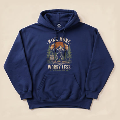 Navy hoodie featuring the "Hike More, Worry Less Bigfoot Hoodie" graphic with mountains, a forest, and a Bigfoot silhouette.