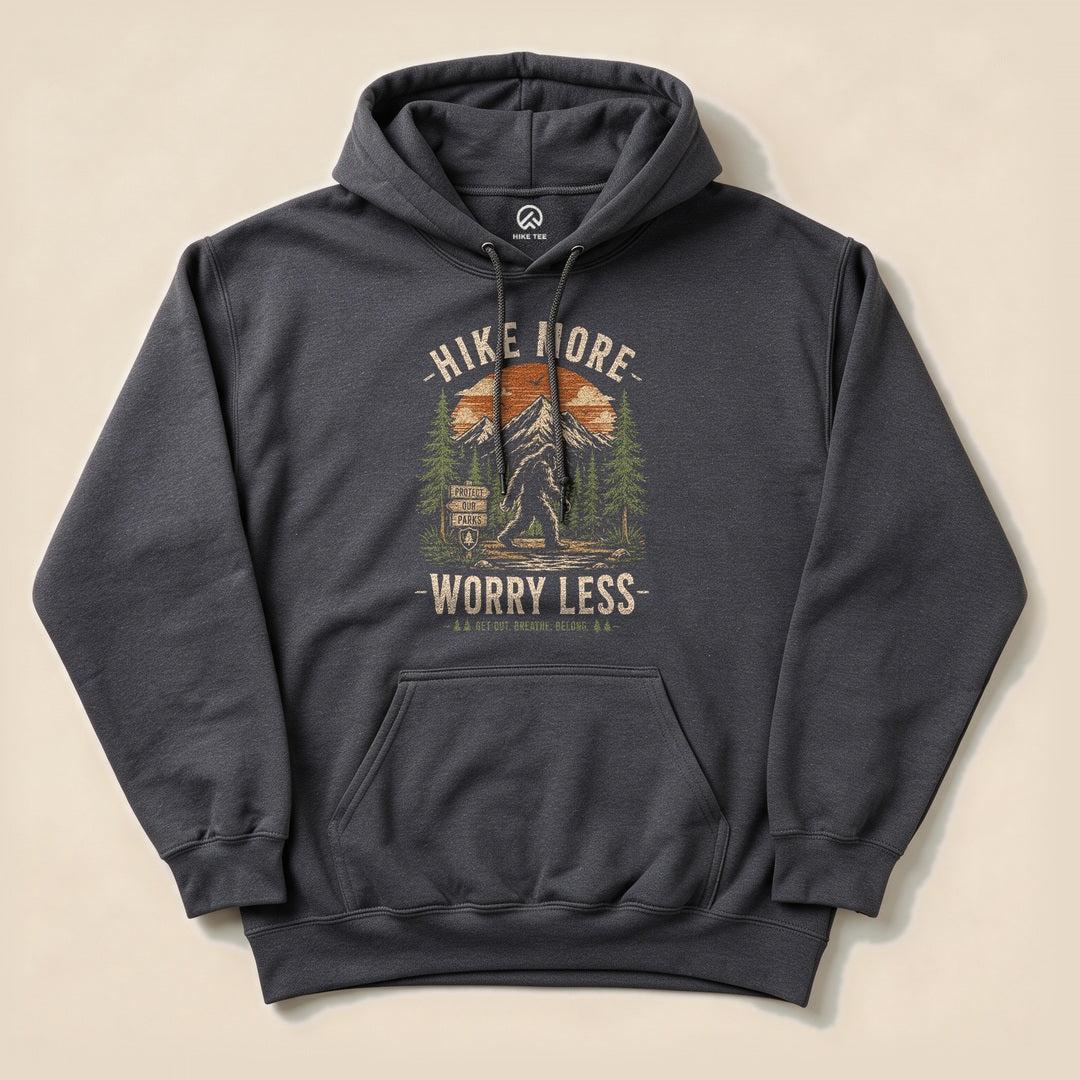 The Hike More, Worry Less Bigfoot Hoodie features a graphic of Bigfoot among trees and mountains, with the slogan above and below.