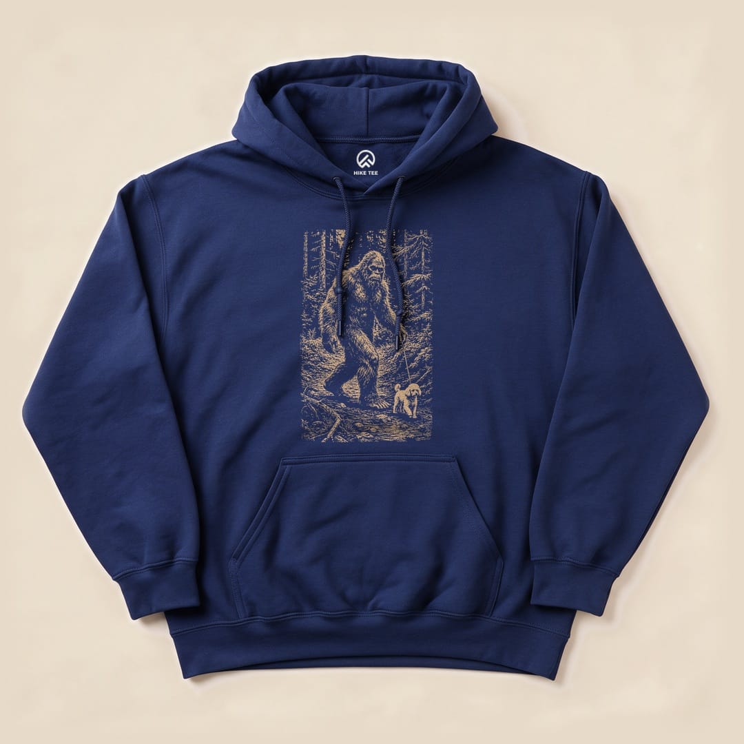 A navy "Walking the Dog Hoodie" features an illustrated graphic of Bigfoot walking with a small dog in a forest setting.