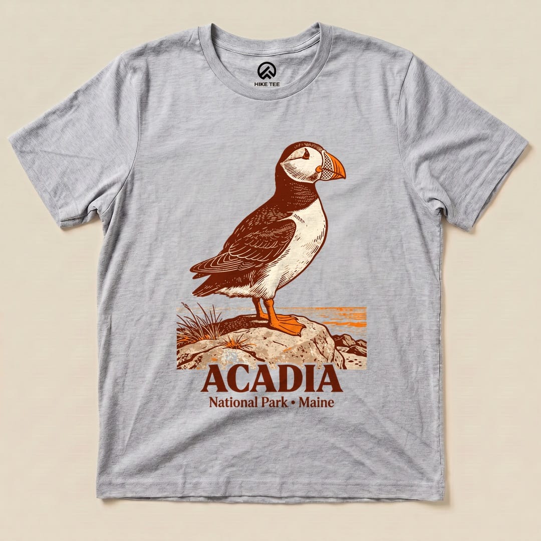 Graphic t-shirt featuring a puffin standing on a rock with the text "Acadia National Park • Maine" below it.