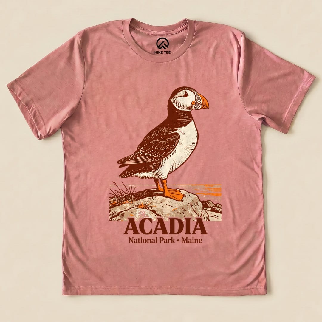 A graphic t-shirt featuring a colorful puffin illustration with "ACADIA National Park • Maine" text in bold letters.