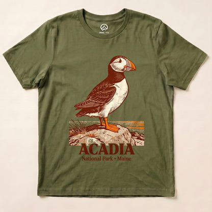 The Acadia National Park Puffin Shirt features a detailed puffin graphic standing on a rock with text below highlighting the park's name.