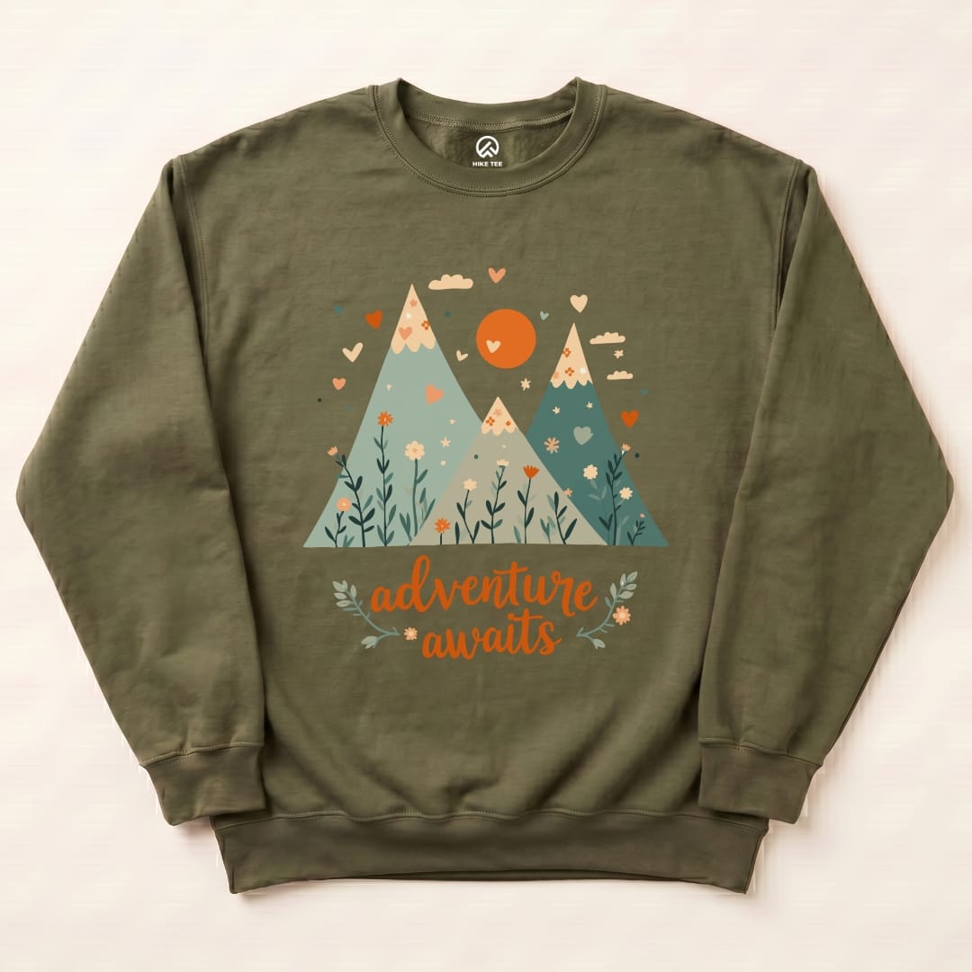Olive green Adventure Awaits Sweatshirt featuring a graphic of mountains, a sun, and floral elements with the slogan "adventure awaits.