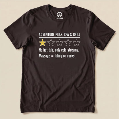 A black graphic t-shirt featuring the slogan "Adventure Peak Spa & Grill" with a humorous review and a single yellow star.