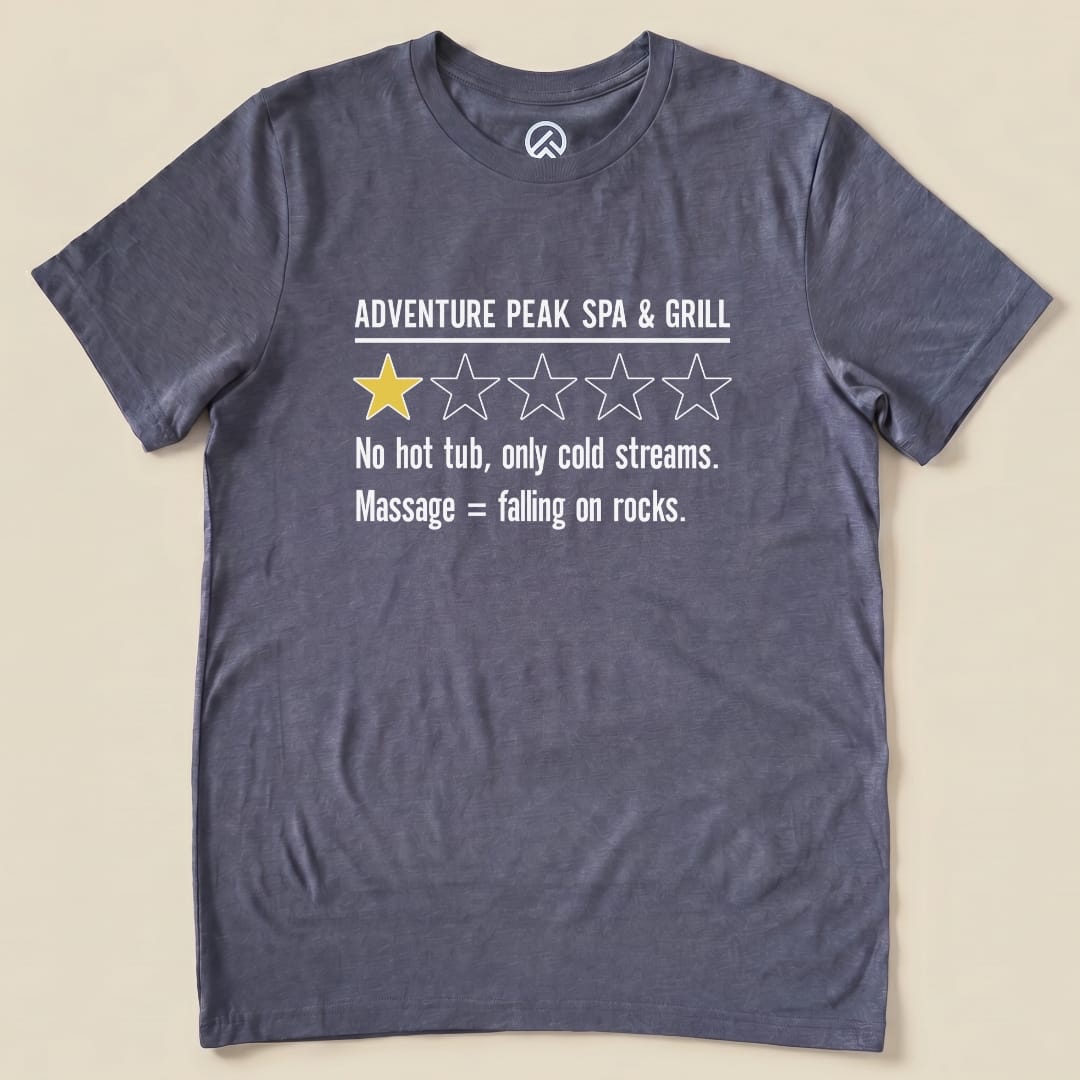 Graphic t-shirt featuring the "Adventure Spa & Grill Review Shirt" with a humorous rating and text about cold streams and rocky massages.