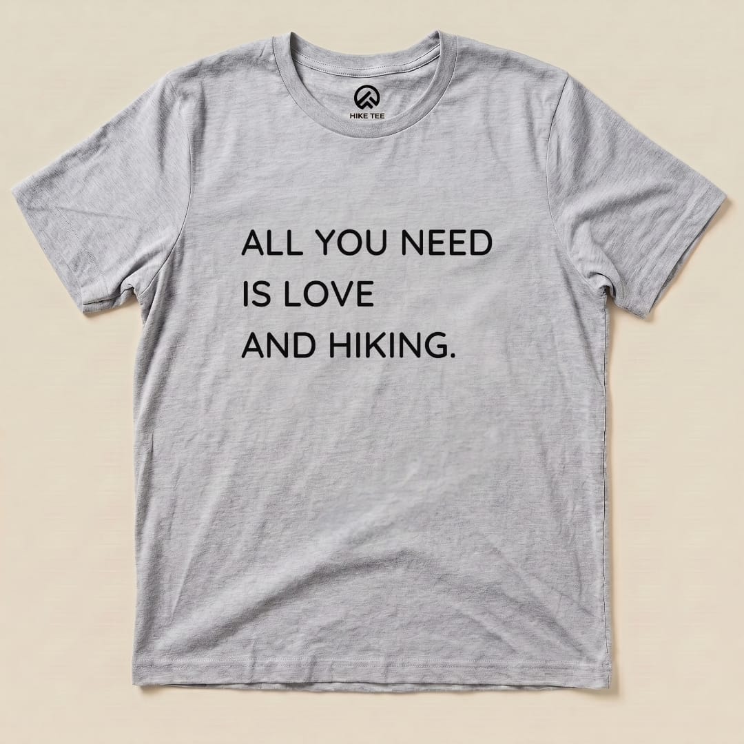 A gray graphic t-shirt with the printed slogan "ALL YOU NEED IS LOVE AND HIKING" prominently displayed.