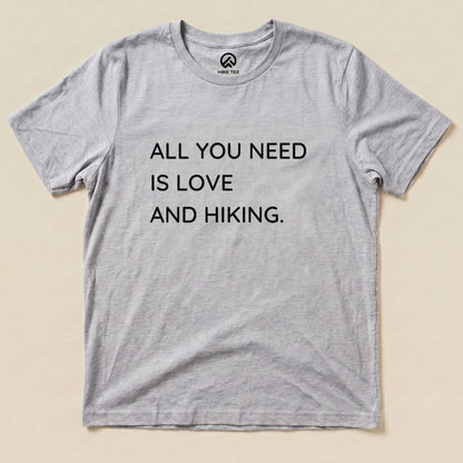 A gray graphic t-shirt with the printed slogan "ALL YOU NEED IS LOVE AND HIKING" prominently displayed.
