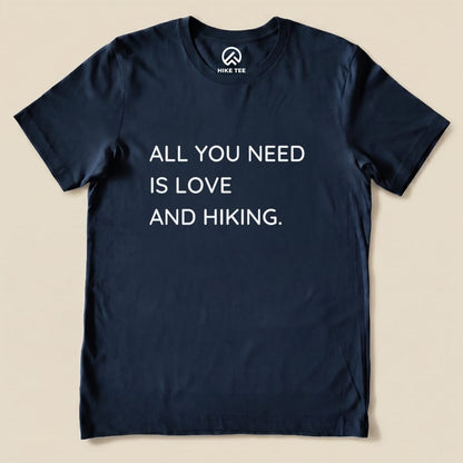 A navy graphic t-shirt featuring the slogan "ALL YOU NEED IS LOVE AND HIKING" prominently displayed on the front.