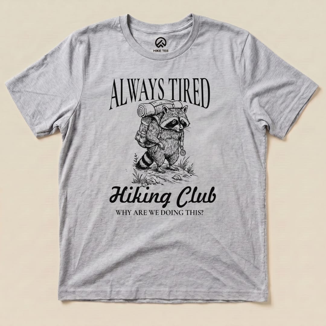 The Always Tired Club Shirt features a raccoon with a backpack and the phrase "Why are we doing this?" in a humorous graphic design.