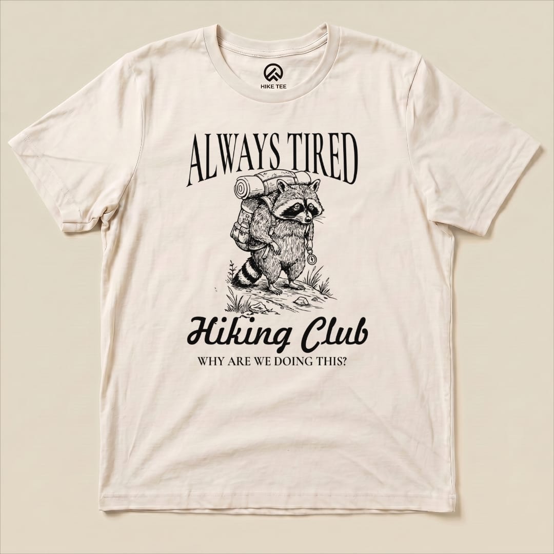 The "Always Tired Club Shirt" features a raccoon with a backpack and the slogan "Why Are We Doing This?" on a graphic t-shirt.
