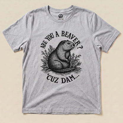 A graphic t-shirt displays a beaver with the humorous text "Are U A Beaver? Cuz Dam..." and decorative foliage on a light background.