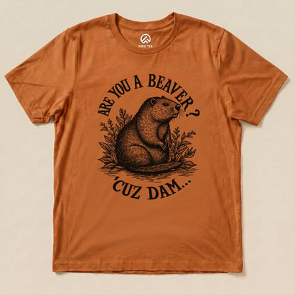 A graphic t-shirt in burnt orange featuring the slogan "Are U A Beaver? Cuz Dam..." with an illustrated beaver and foliage design.