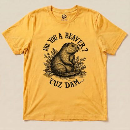 A graphic t-shirt in vibrant yellow featuring the text "Are U A Beaver? Cuz Dam..." alongside an illustration of a beaver surrounded by foliage.