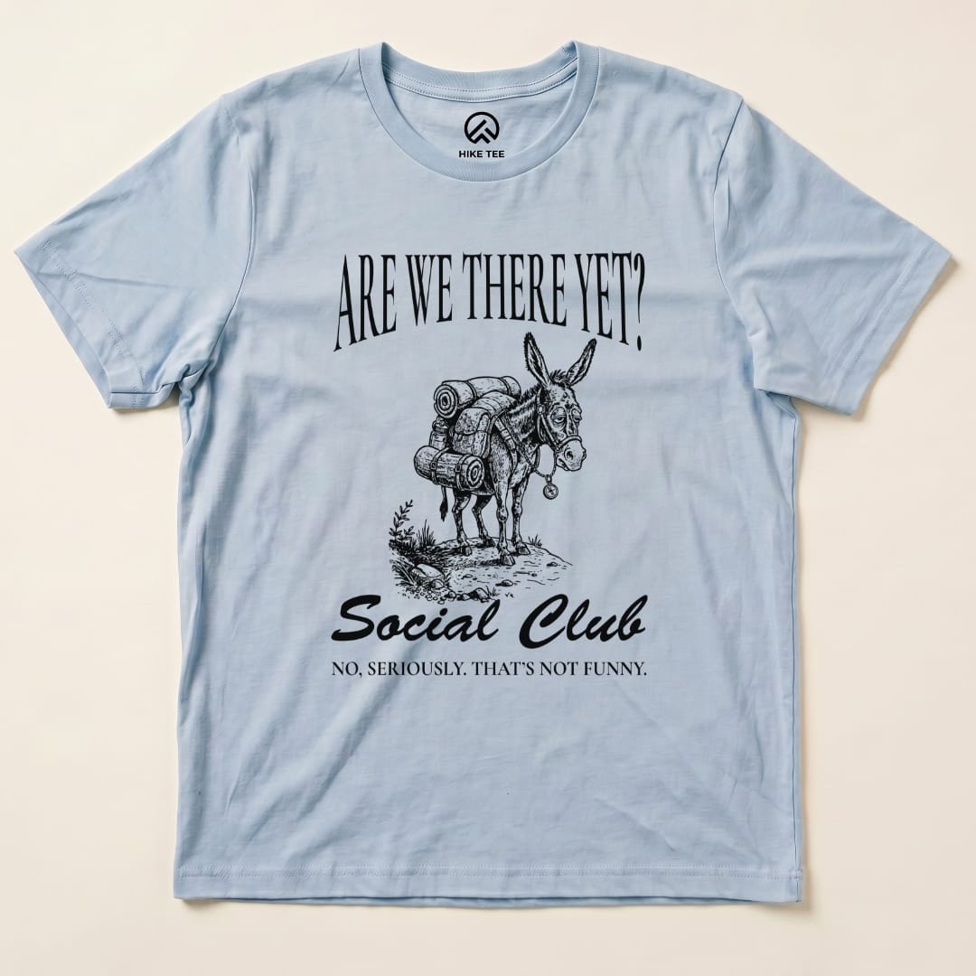 Graphic t-shirt featuring a donkey with backpacks, printed text reads "Are We There Yet? Social Club" and "No, seriously. That's not funny.