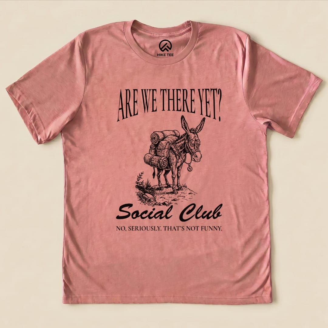 A pink graphic t-shirt features a donkey loaded with gear, accompanied by the text "Are We There Yet? Social Club" and "No, seriously. That's not funny.