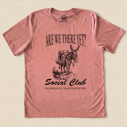 A pink graphic t-shirt features a donkey loaded with gear, accompanied by the text "Are We There Yet? Social Club" and "No, seriously. That's not funny.