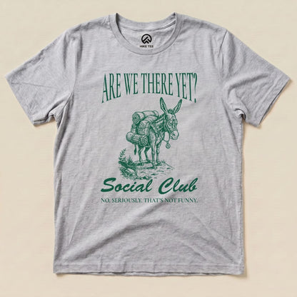 A gray graphic t-shirt features a packed donkey and the text "Are We There Yet? Social Club" with a humorous tagline below.