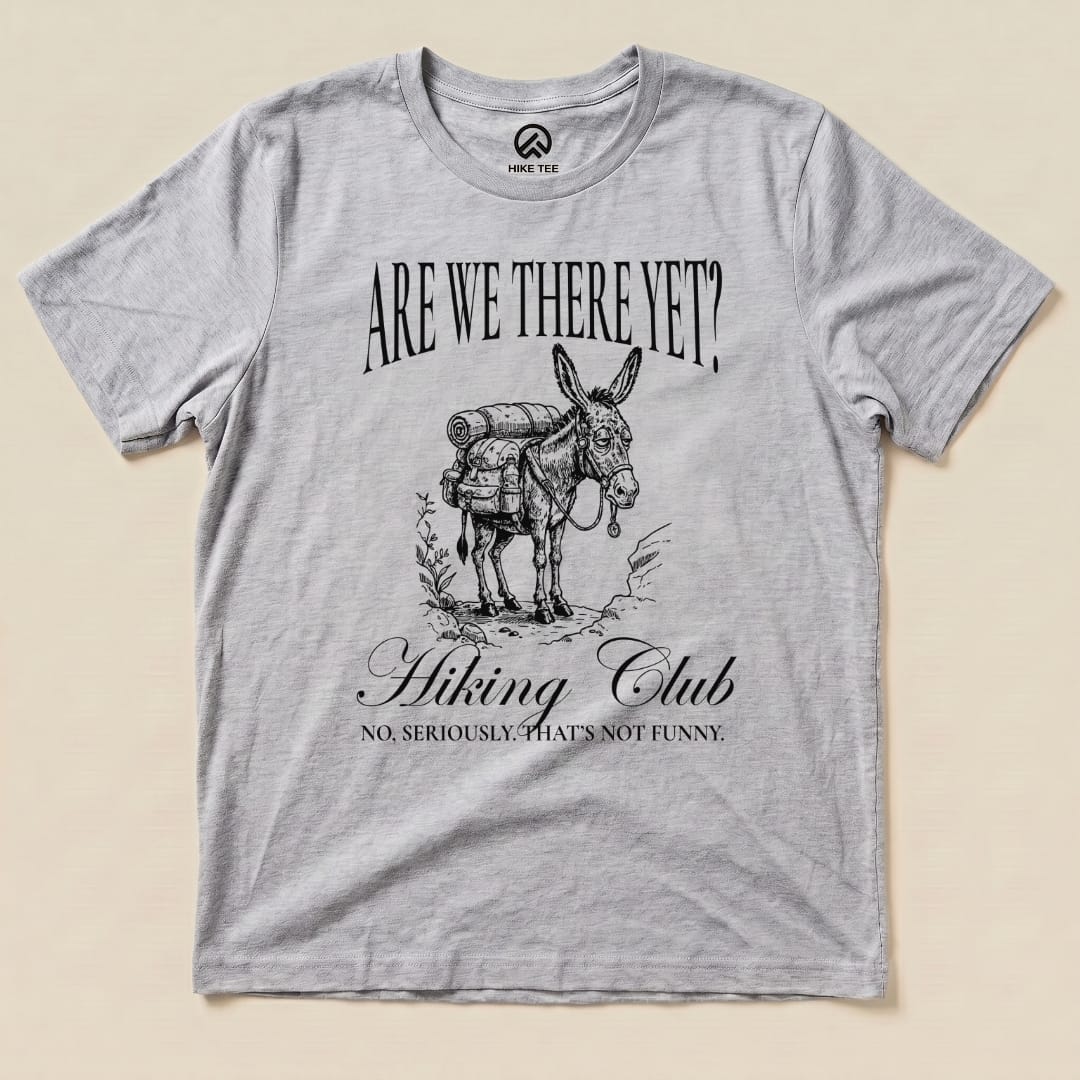 A gray graphic t-shirt featuring a donkey with a backpack and the text "Are We There Yet? Hiking Club" in a humorous design.