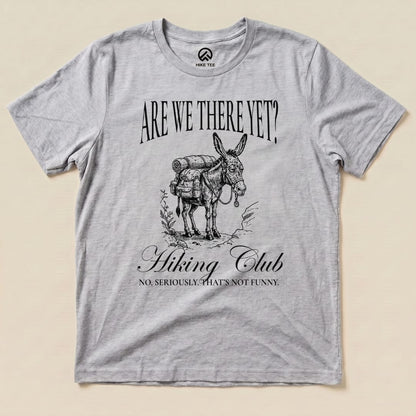 A gray graphic t-shirt featuring a donkey with a backpack and the text "Are We There Yet? Hiking Club" in a humorous design.