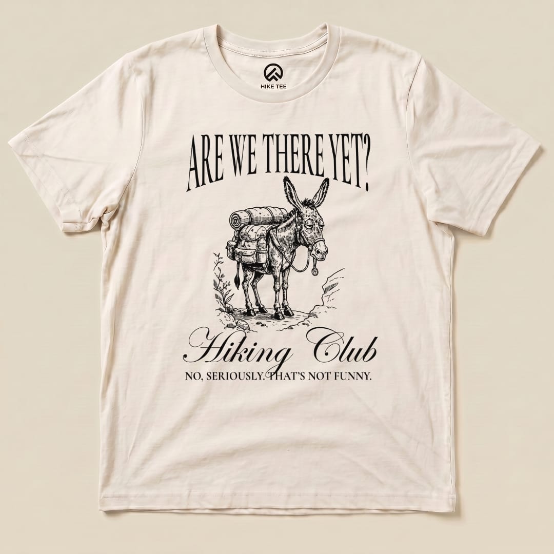 A flat view of the "Are We There Yet? Club Shirt" featuring a donkey with a backpack and the slogan "No, seriously. That's not funny.