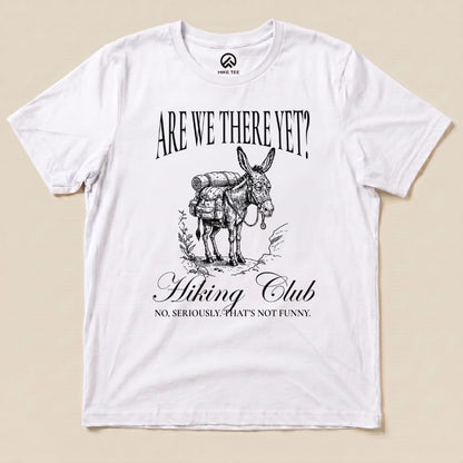 Graphic t-shirt features a donkey with a backpack and the phrase "Are We There Yet? Hiking Club" in bold lettering.