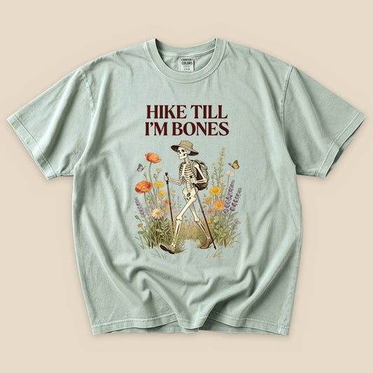Bay Hike Till I'm Bones T-Shirt with a skeleton hiker among wildflowers graphic