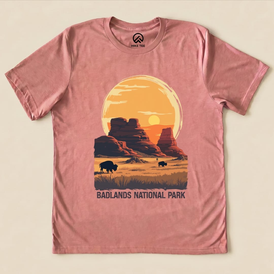 A pink graphic t-shirt features a sunset over Badlands National Park with bison silhouettes and "BADLANDS NATIONAL PARK" text.